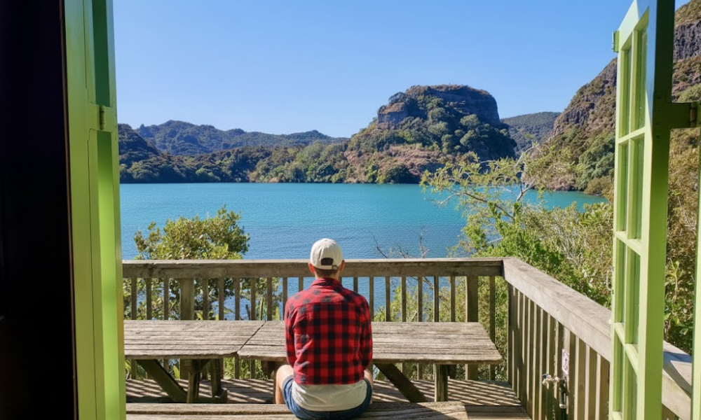 A man sitting at a wooden picnic table admiring the view over Whangaroa Harbour